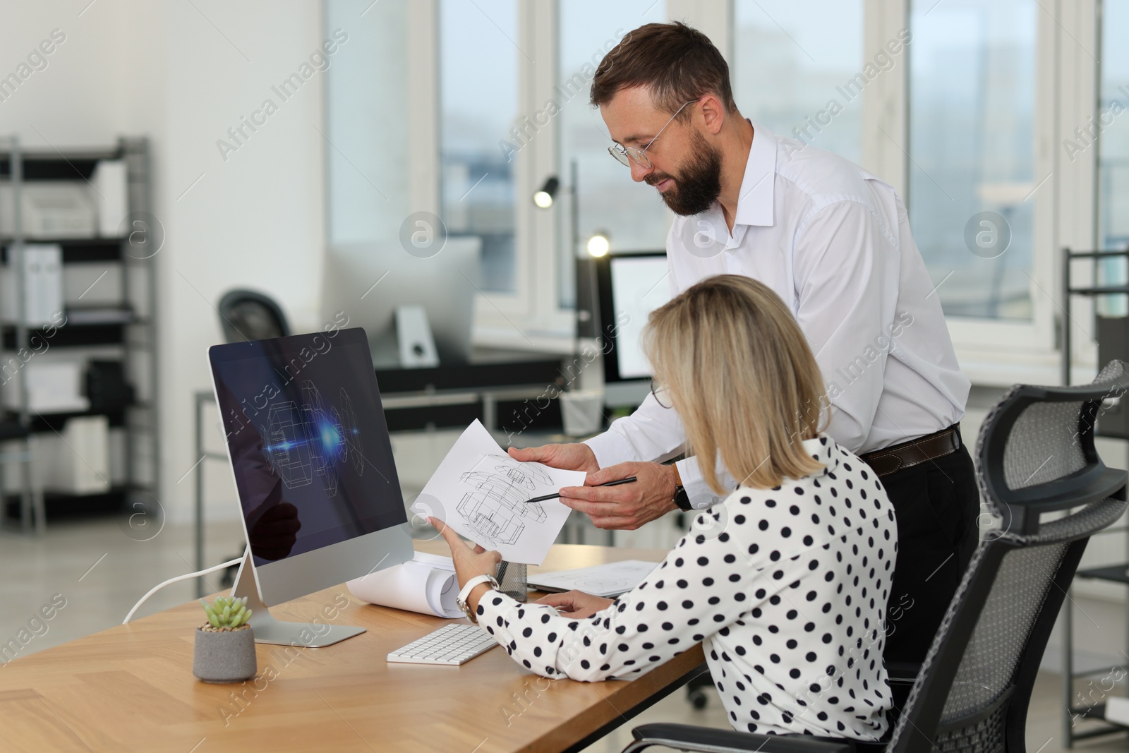 Photo of Technicians making digital engineering drawing on computer at desk in office