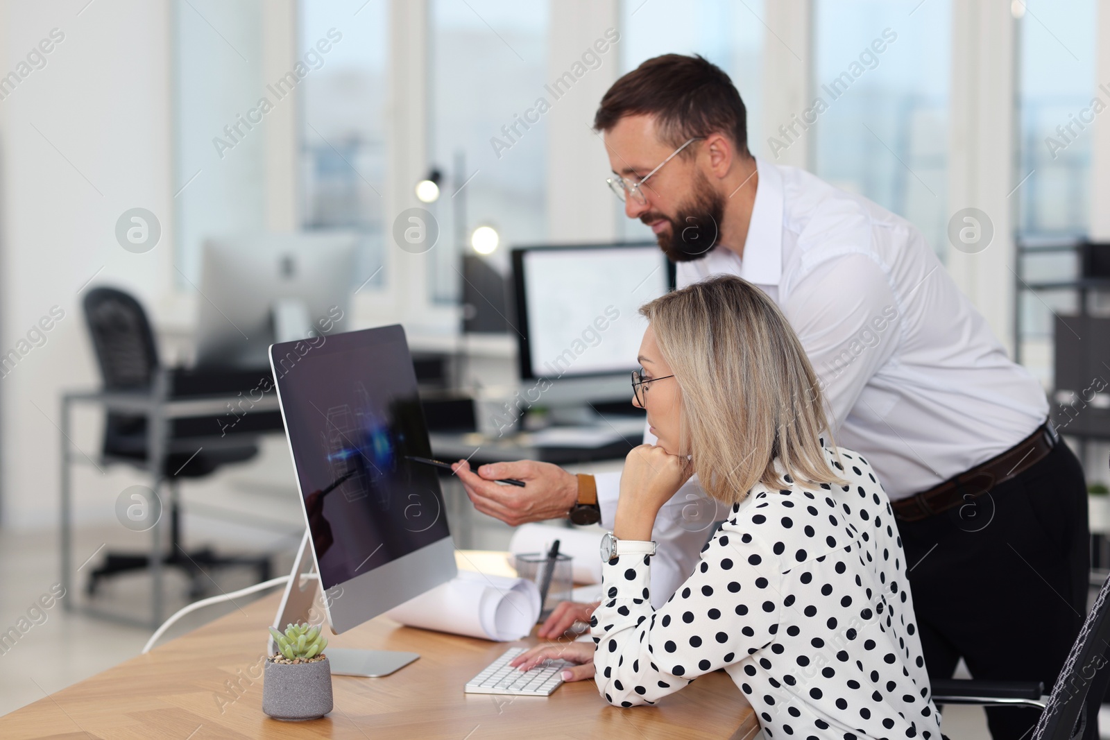 Photo of Technicians making digital engineering drawing on computer at desk in office