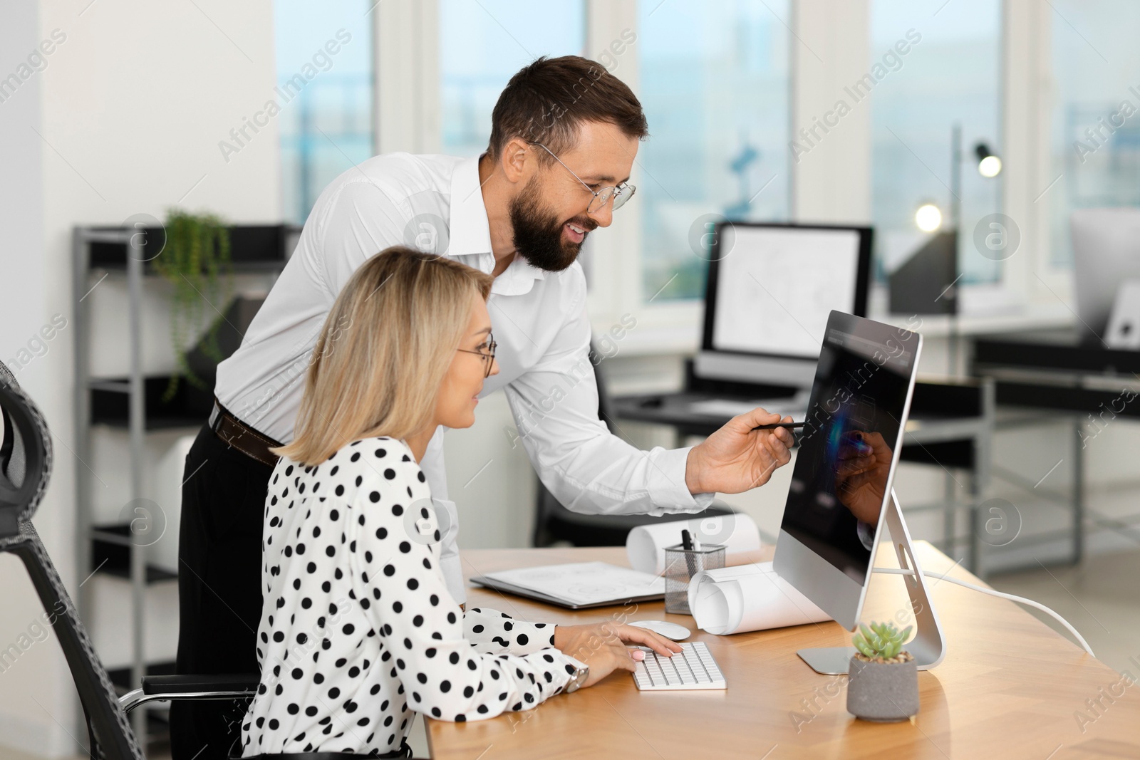 Photo of Technicians making digital engineering drawing on computer at desk in office