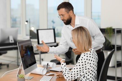 Photo of Technicians making digital engineering drawing on computer at desk in office