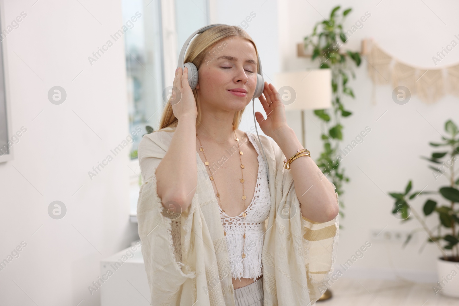 Photo of Feng shui. Young woman with headphones listening to music at home