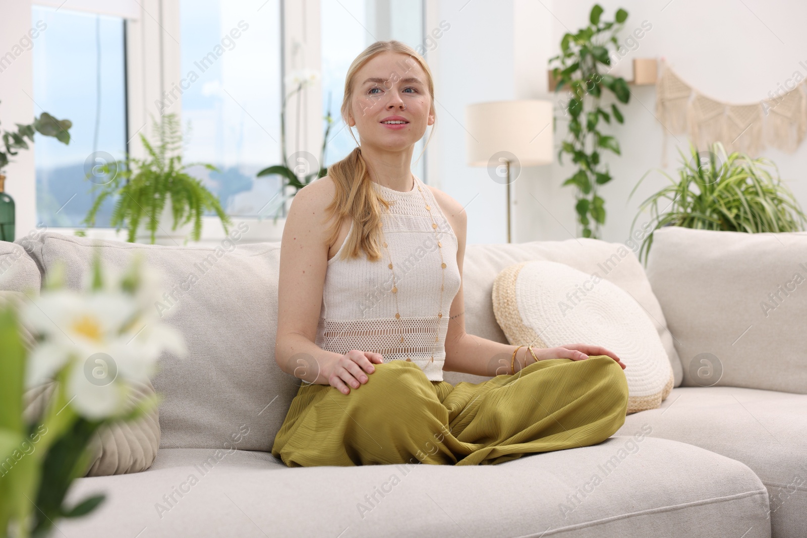 Photo of Feng shui. Young woman meditating on couch at home