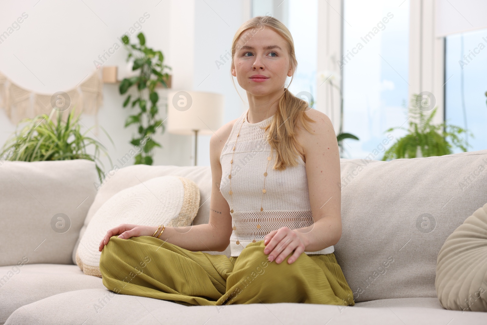 Photo of Feng shui. Young woman meditating on couch at home