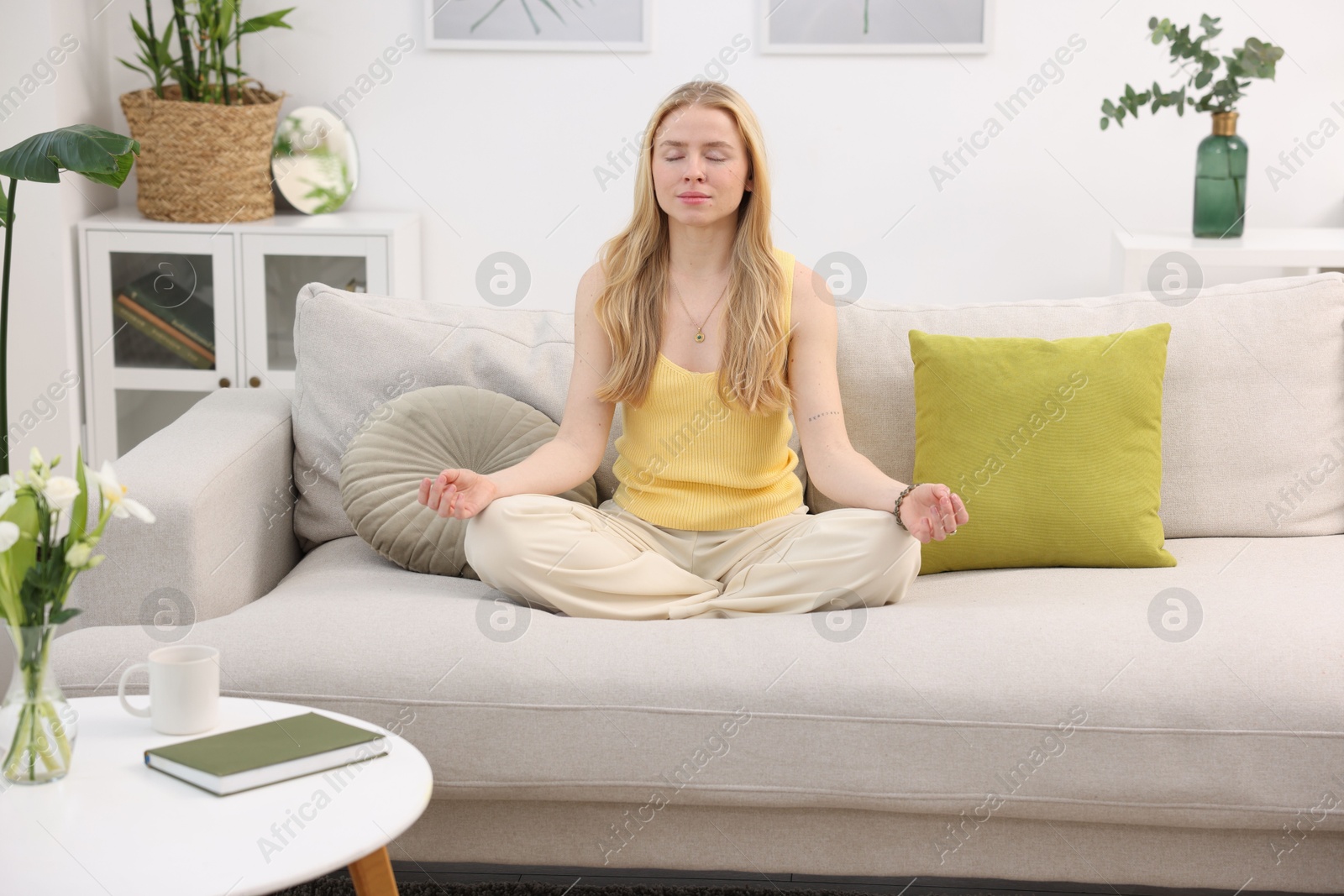 Photo of Feng shui. Young woman meditating on couch at home