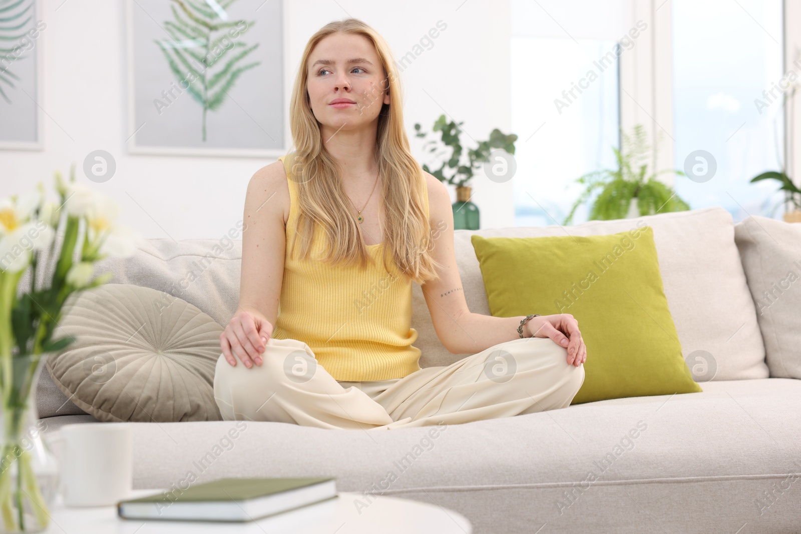 Photo of Feng shui. Young woman meditating on couch at home