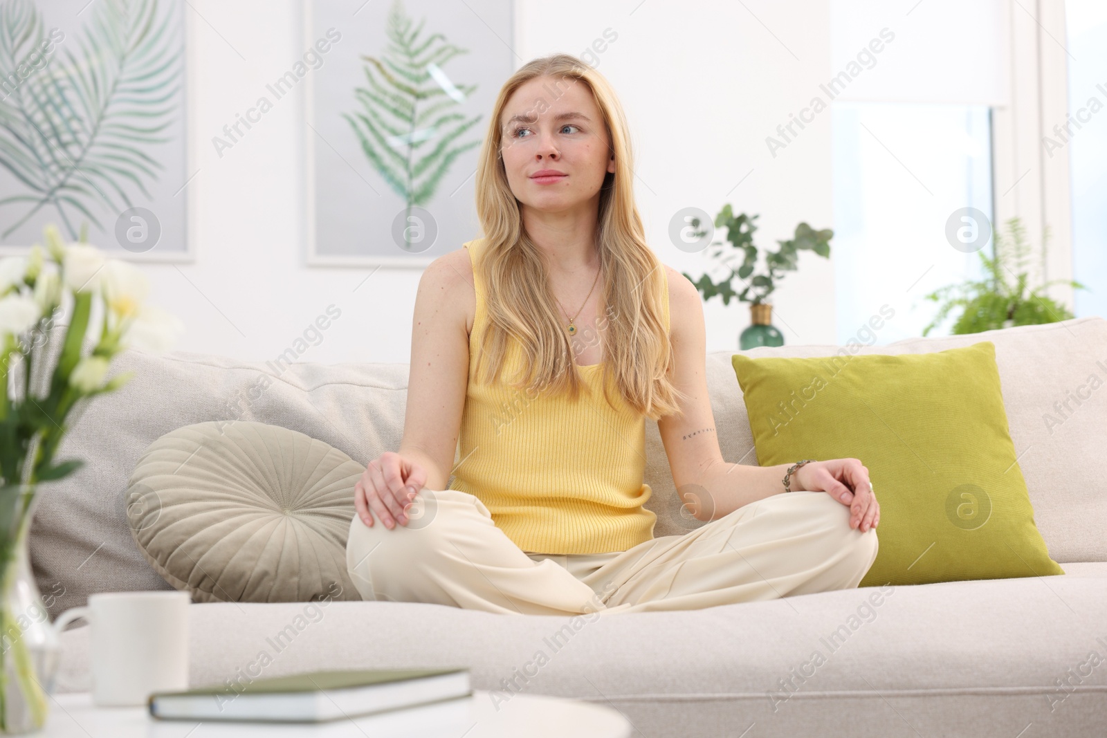 Photo of Feng shui. Young woman meditating on couch at home