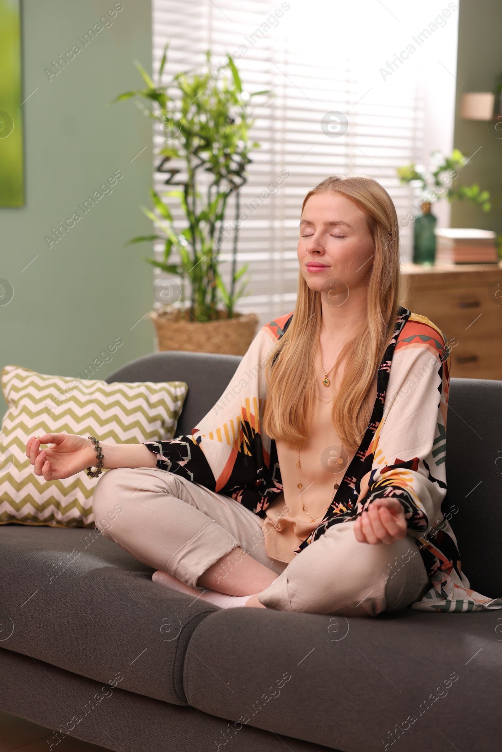 Photo of Feng shui. Young woman meditating on couch at home''