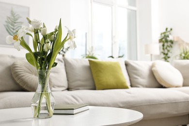 Photo of Feng shui. Vase with flowers and book on white table indoors. Space for text