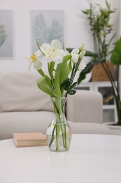 Photo of Feng shui. Vase with flowers and book on white table indoors