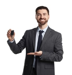 Photo of Cheerful salesman showing car key on white background