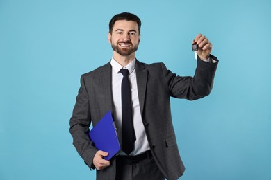 Photo of Cheerful salesman with car key and clipboard on light blue background