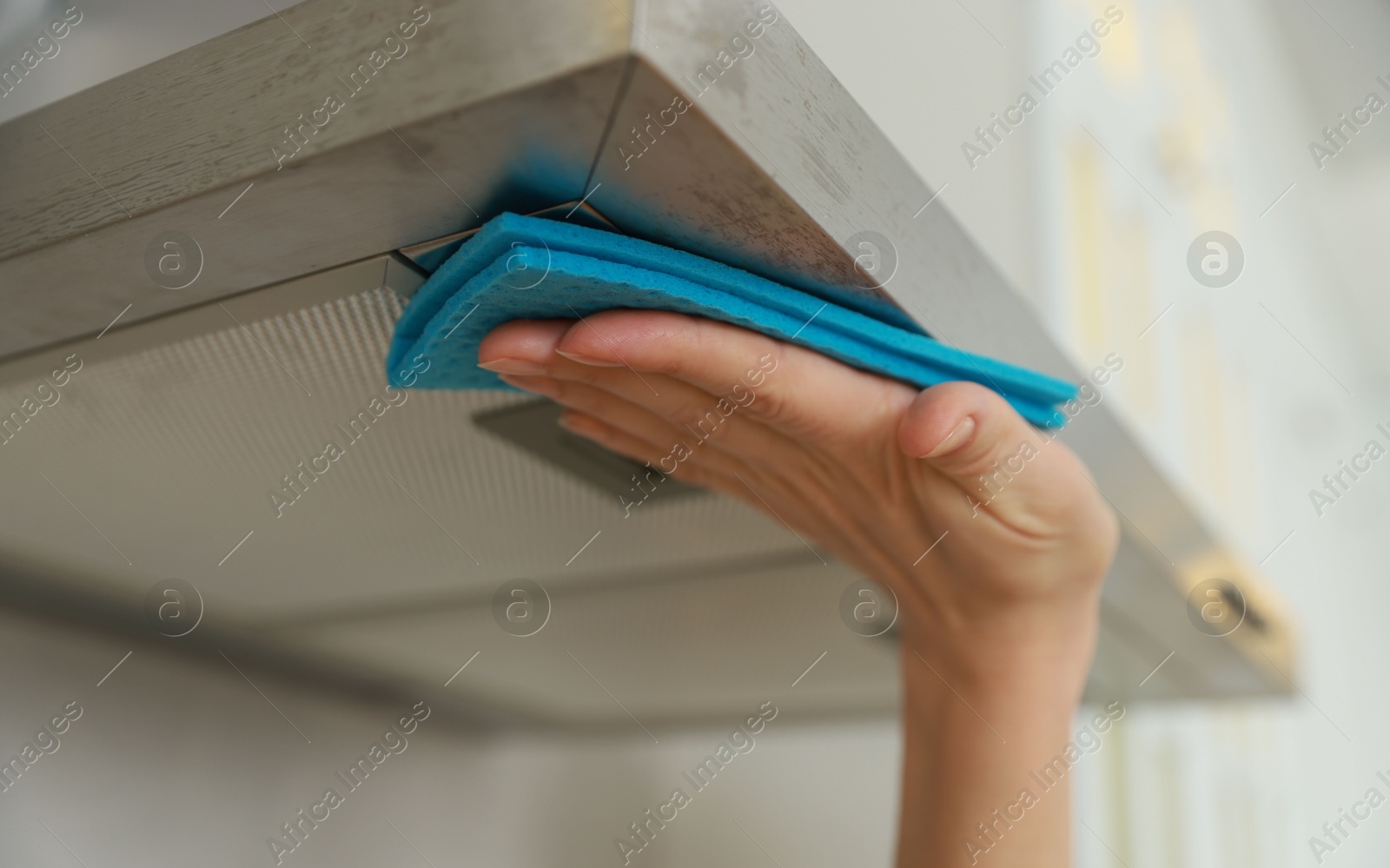 Photo of Woman cleaning kitchen hood with rag indoors, closeup