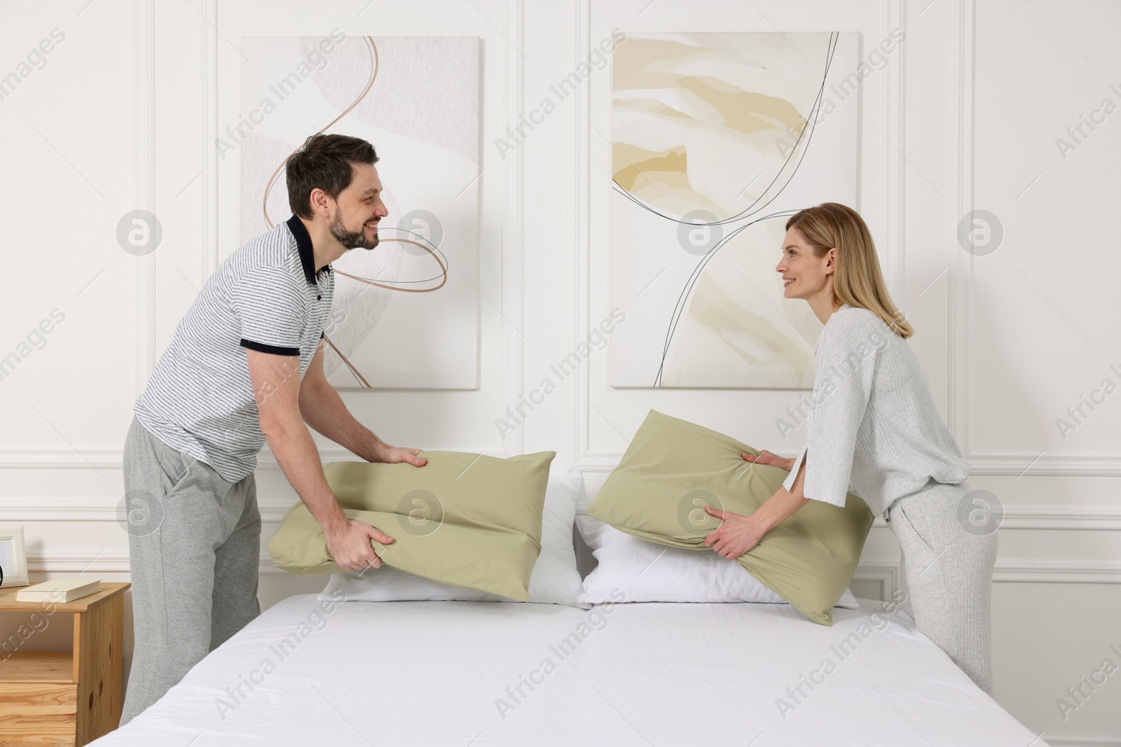 Photo of Couple changing bed linens at home. Domestic chores