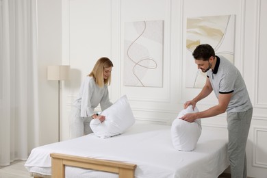 Photo of Couple changing bed linens at home. Domestic chores