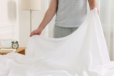 Photo of Man changing bed linens at home, closeup