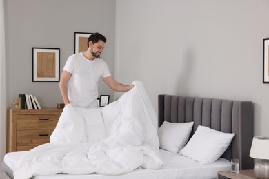 Photo of Man changing bed linens at home. Space for text