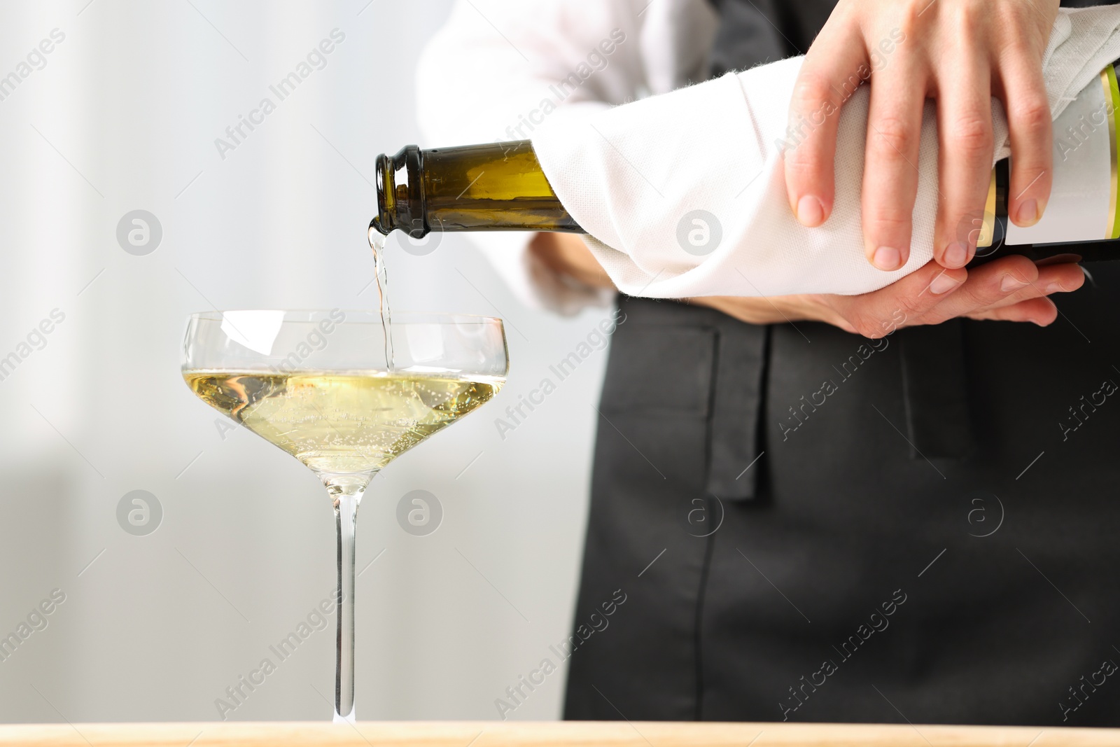 Photo of Waiter pouring champagne into glass indoors, closeup