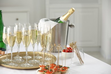 Photo of Champagne, strawberries and canapes with red caviar on white table