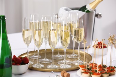 Photo of Champagne, strawberries and canapes with red caviar on white table