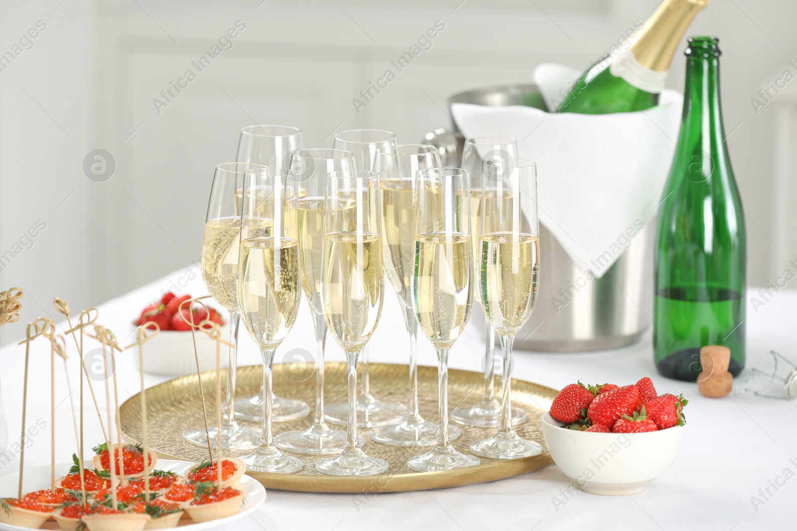 Photo of Champagne, strawberries and canapes with red caviar on white table