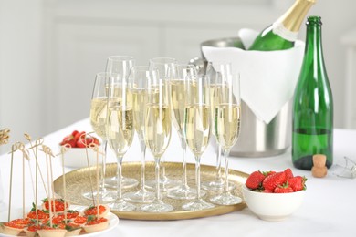 Photo of Champagne, strawberries and canapes with red caviar on white table