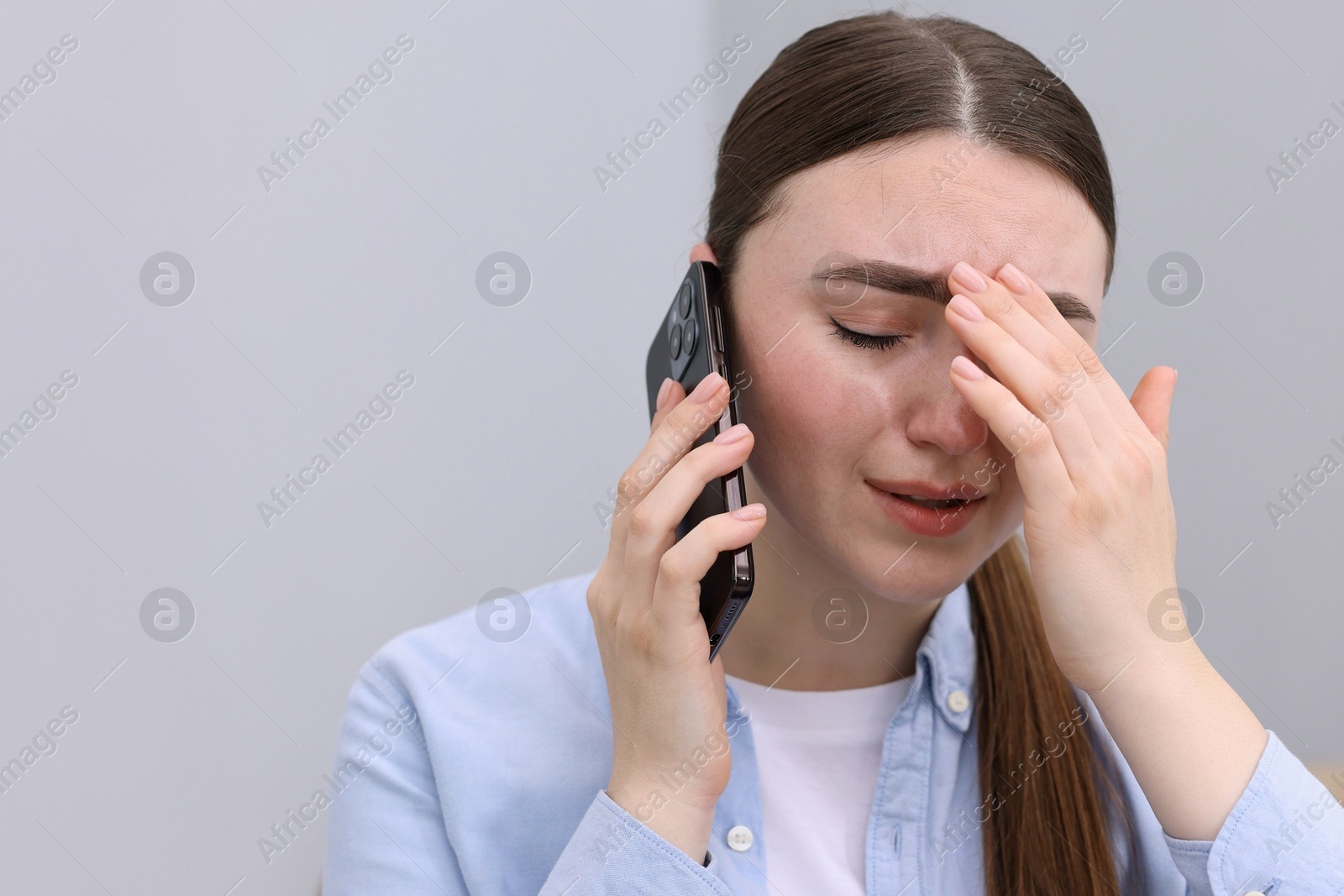 Photo of Stressed woman calling hotline for mental health help on grey background. Space for text