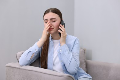 Photo of Stressed woman calling hotline for mental health help in armchair at home