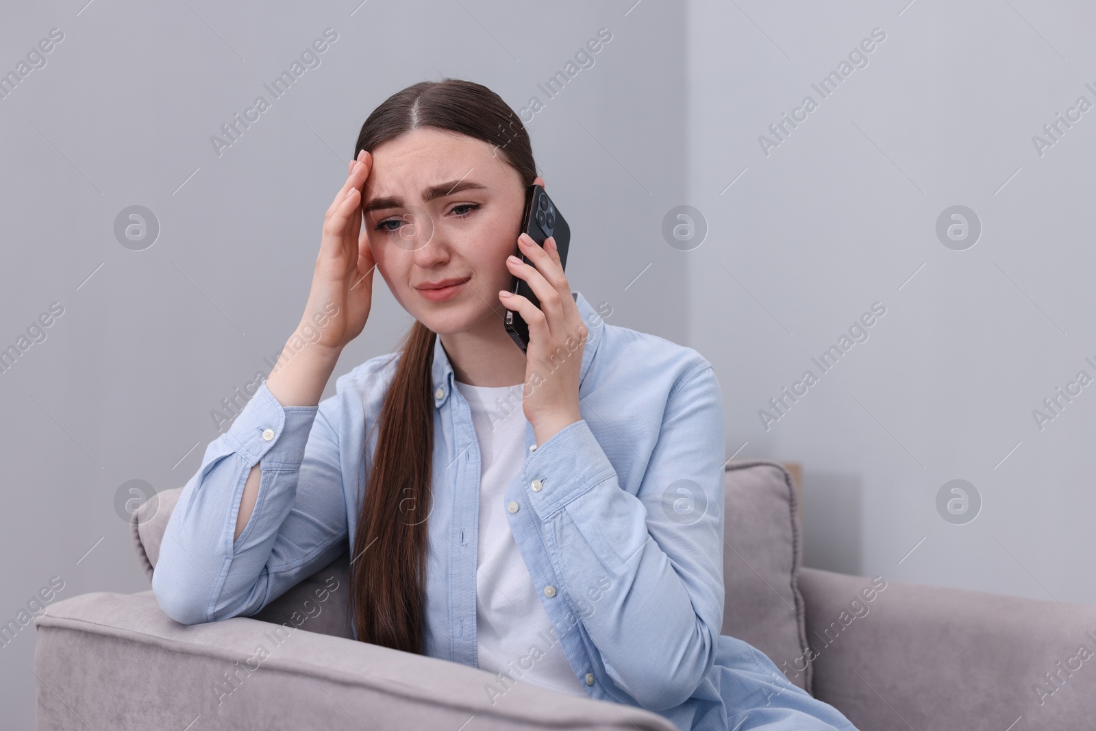 Photo of Stressed woman calling hotline for mental health help in armchair at home