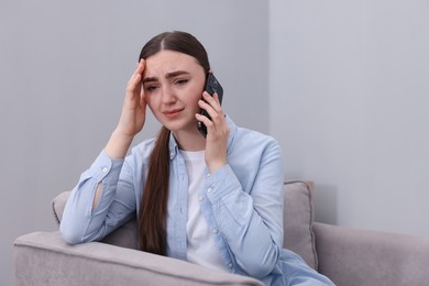 Photo of Stressed woman calling hotline for mental health help in armchair at home