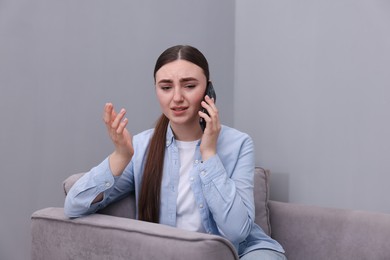 Photo of Stressed woman calling hotline for mental health help in armchair at home