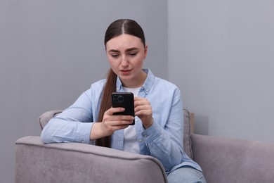 Photo of Stressed woman calling hotline for mental health help in armchair at home