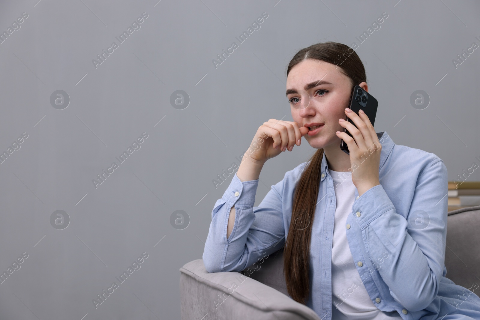 Photo of Stressed woman calling hotline for mental health help in armchair at home. Space for text