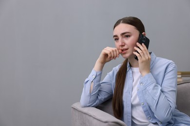 Photo of Stressed woman calling hotline for mental health help in armchair at home. Space for text