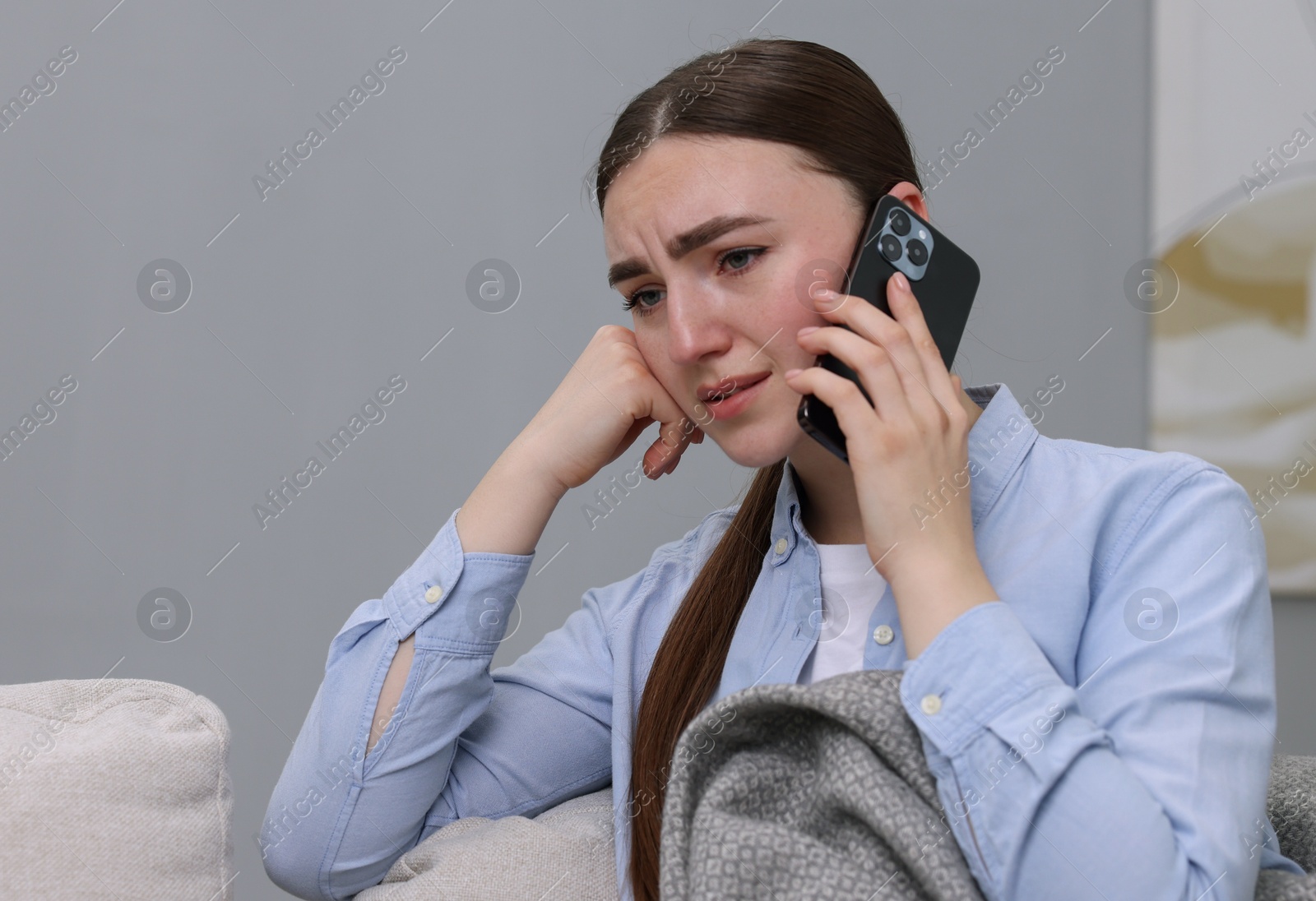 Photo of Depressed woman calling hotline for mental health help on sofa at home. Space for text