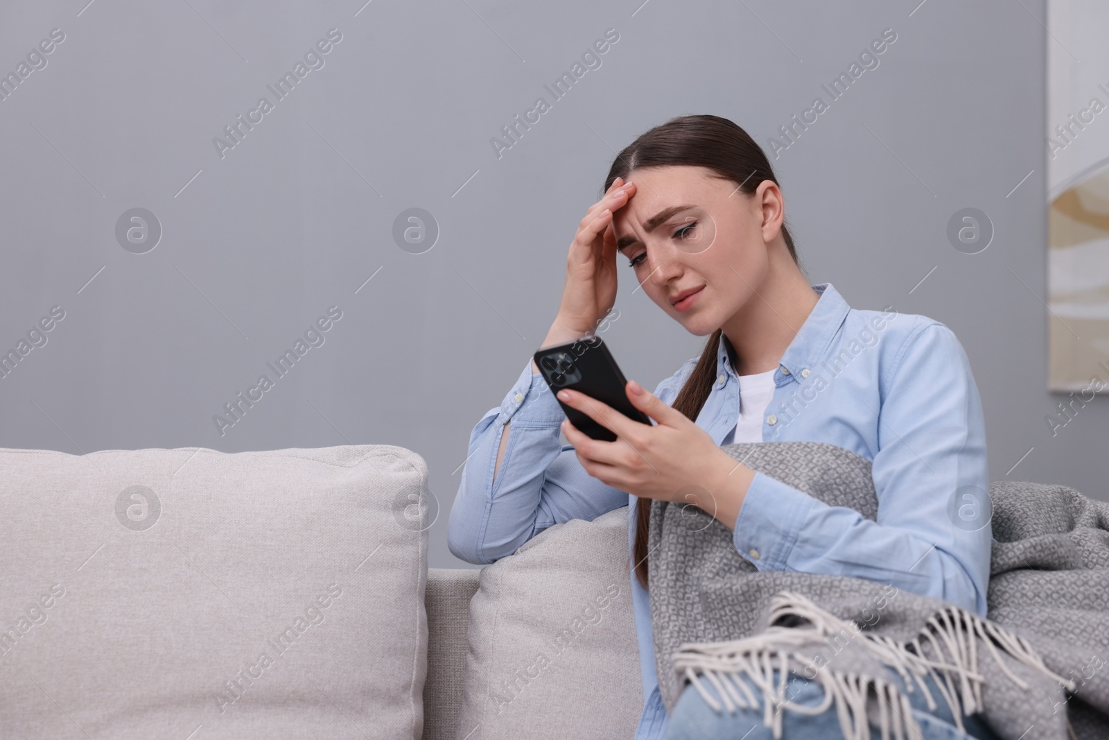 Photo of Depressed woman calling hotline for mental health help on sofa at home. Space for text