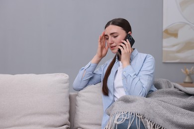 Photo of Depressed woman calling hotline for mental health help on sofa at home. Space for text