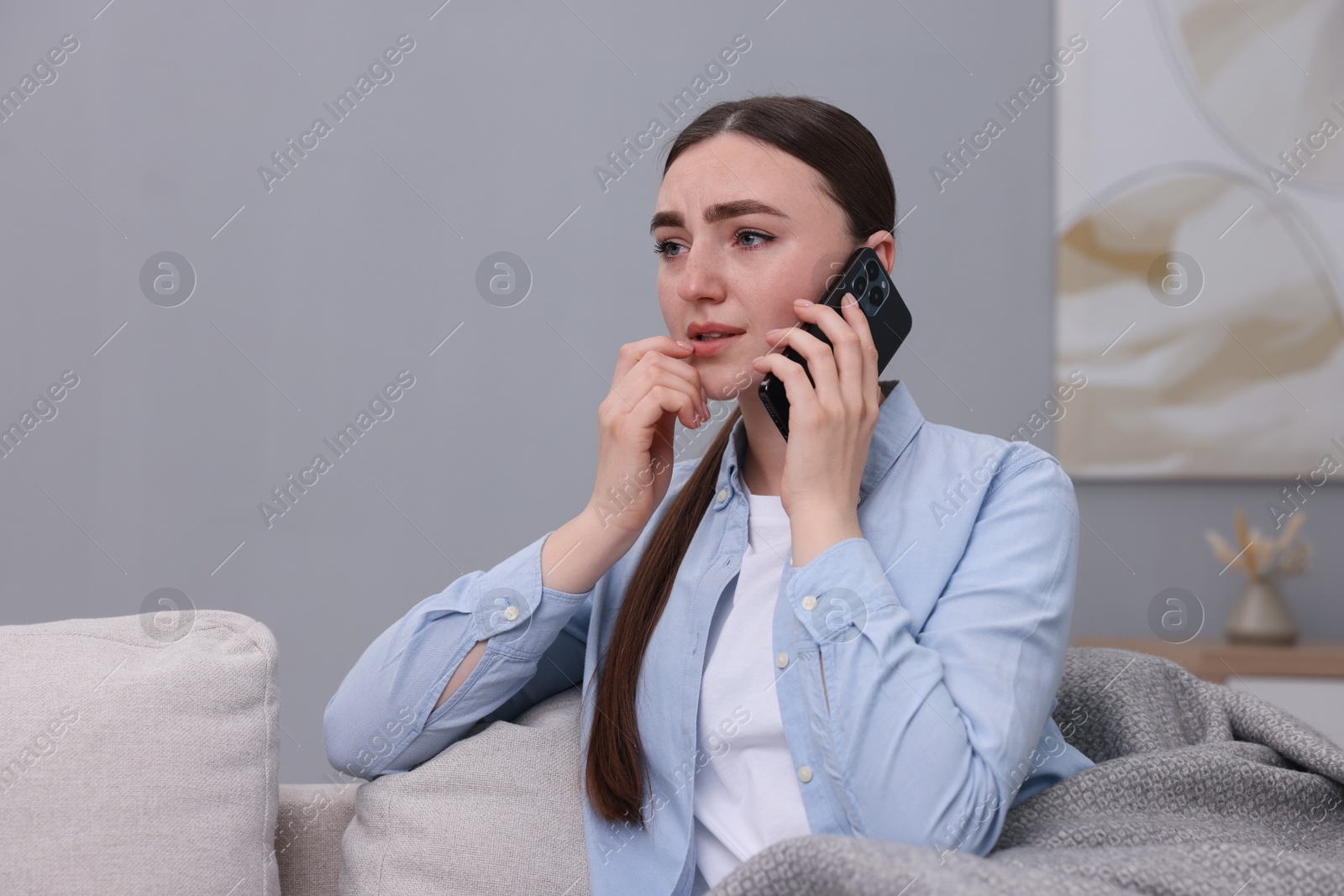 Photo of Depressed woman calling hotline for mental health help on sofa at home. Space for text