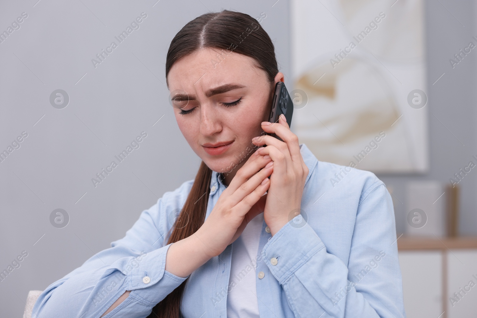 Photo of Stressed woman calling hotline for mental health help at home