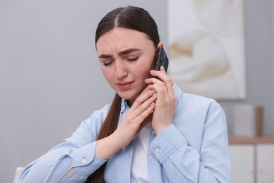 Photo of Stressed woman calling hotline for mental health help at home