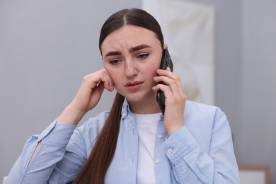 Photo of Stressed woman calling hotline for mental health help at home