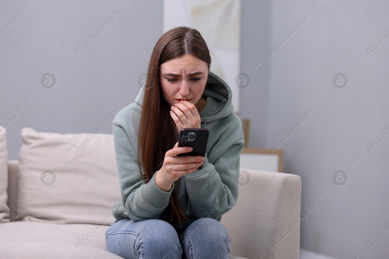 Photo of Depressed woman calling hotline for mental health help on sofa at home