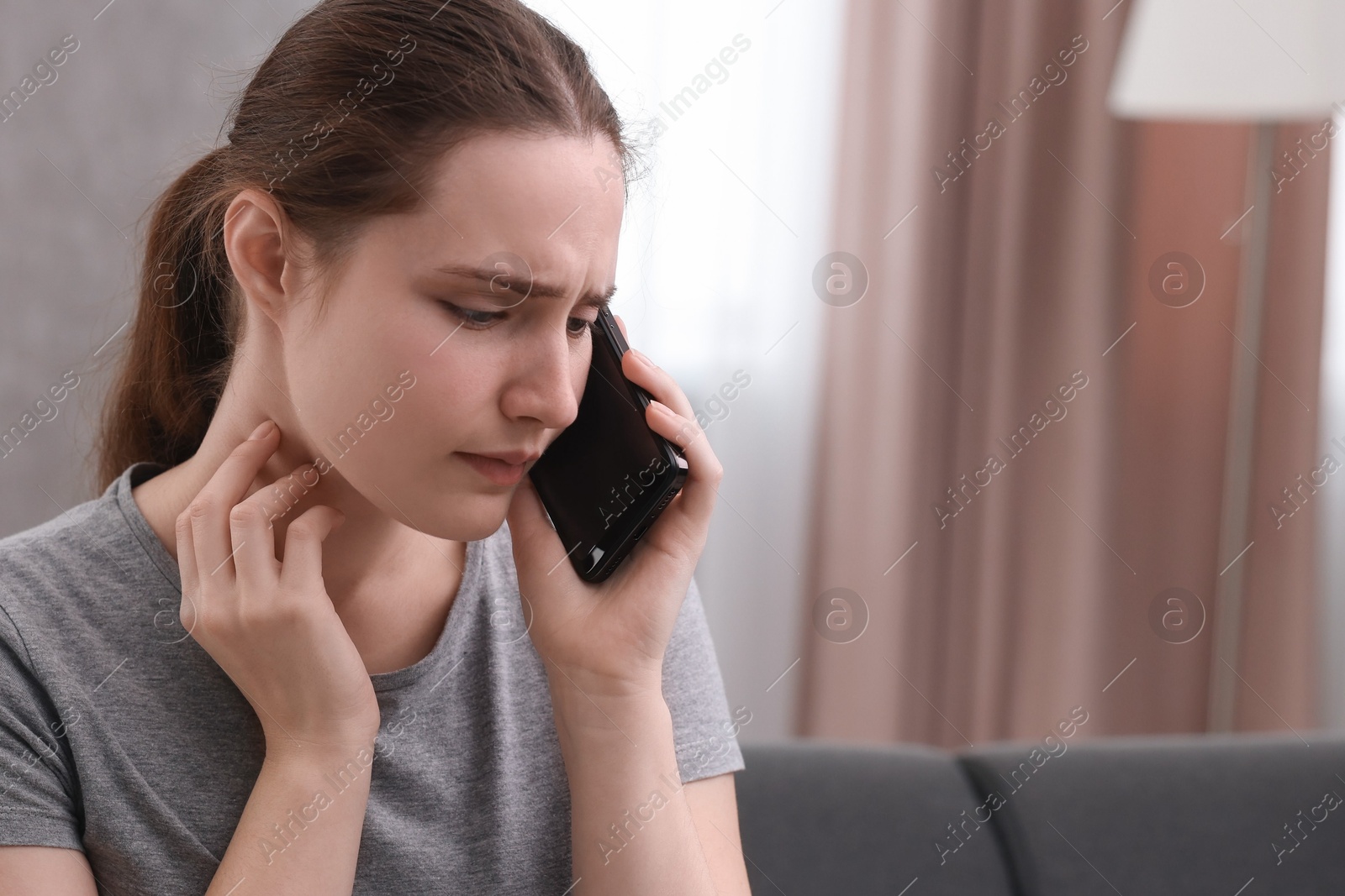 Photo of Depressed woman calling hotline for mental health help on sofa at home. Space for text