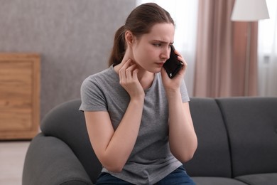 Photo of Depressed woman calling hotline for mental health help on sofa at home