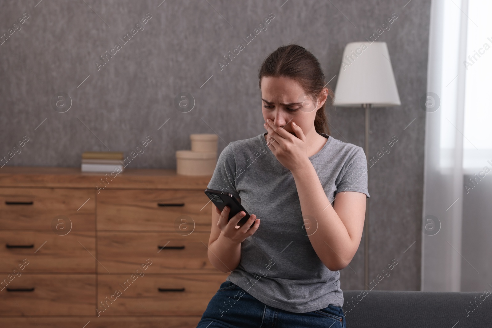 Photo of Depressed woman calling hotline for mental health help on sofa at home