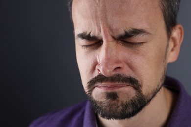 Photo of Sad man crying on grey background, closeup. Space for text