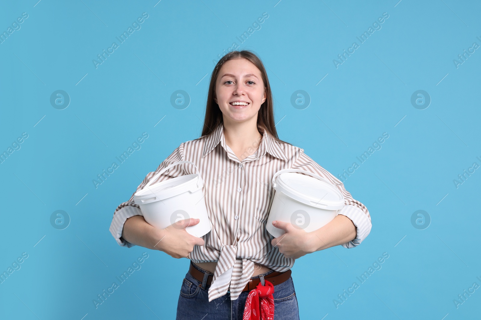 Photo of Woman with buckets of paint on light blue background