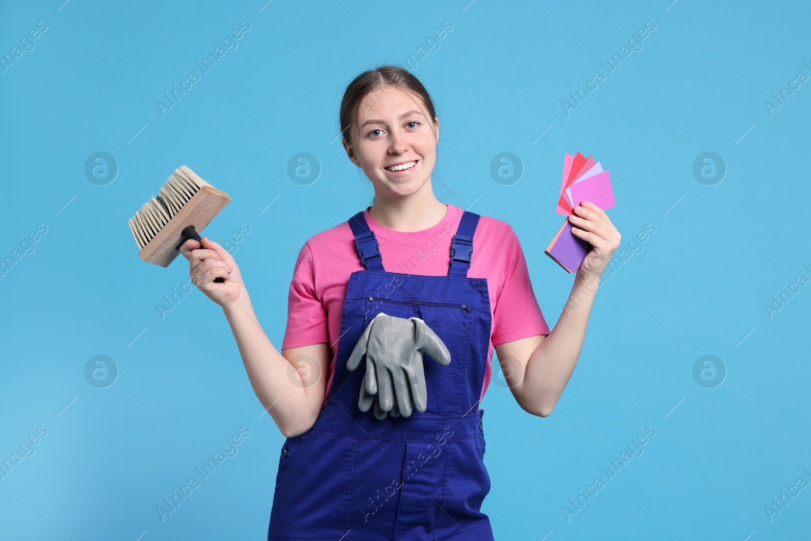 Photo of Professional painter with brush and color samples on light blue background