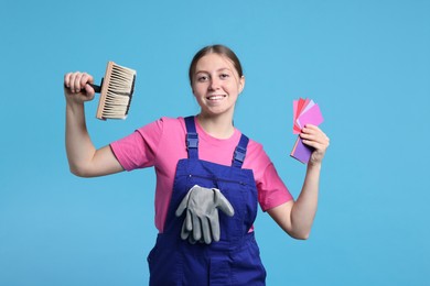 Photo of Professional painter with brush and color samples on light blue background