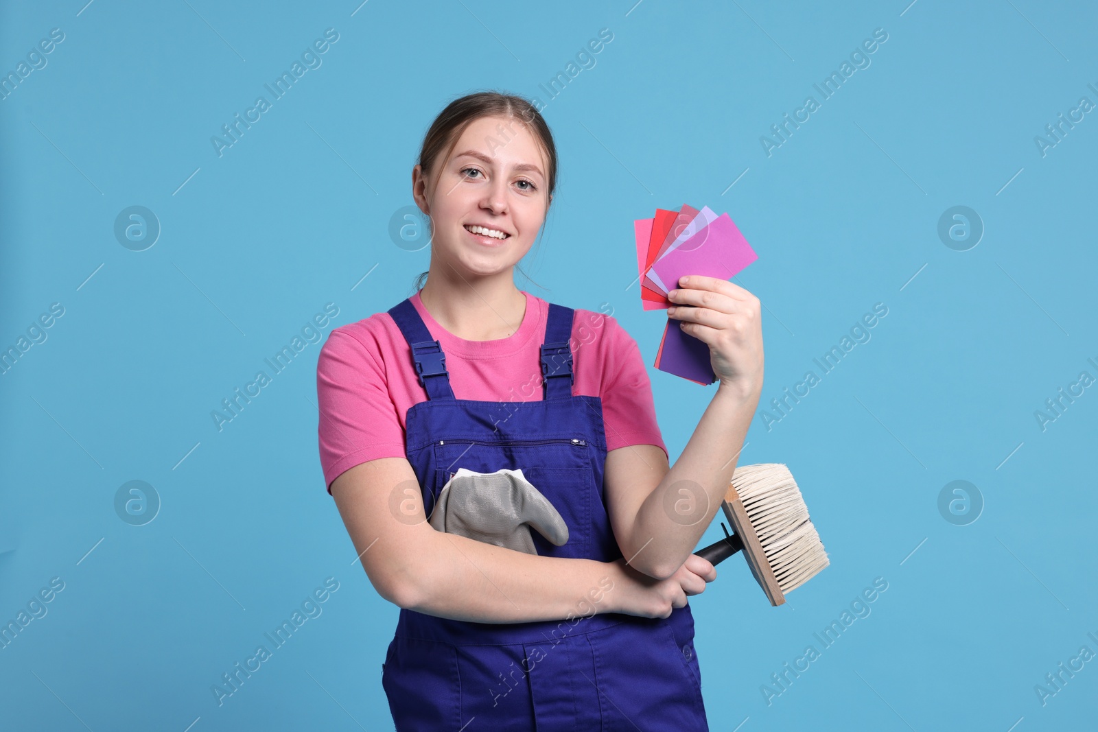 Photo of Professional painter with brush and color samples on light blue background