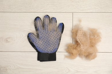 Photo of Grooming glove and pile of pet's hair on floor, top view